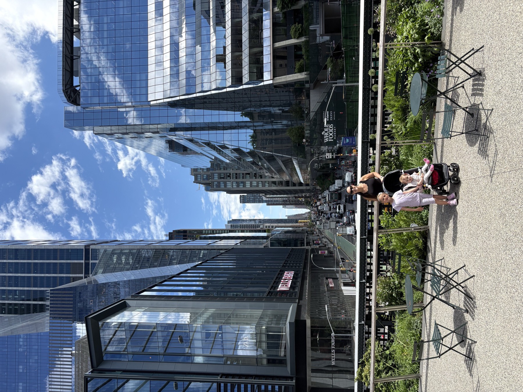 The High Line looking downtown with glass towers, traffic below, and the family parked in the middle of it
